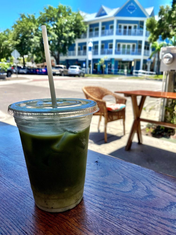 An iced matcha on an outdoor table, a pastel three-story Gulfport building behind
