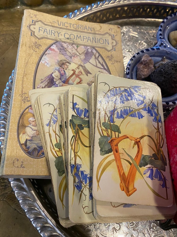 A Victorian Fairy Companion oracle deck fanned on a silver tray