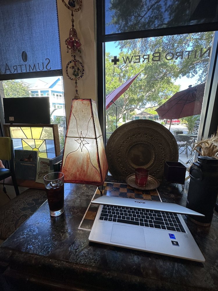 A laptop and an iced coffee at a window table under a hide lantern