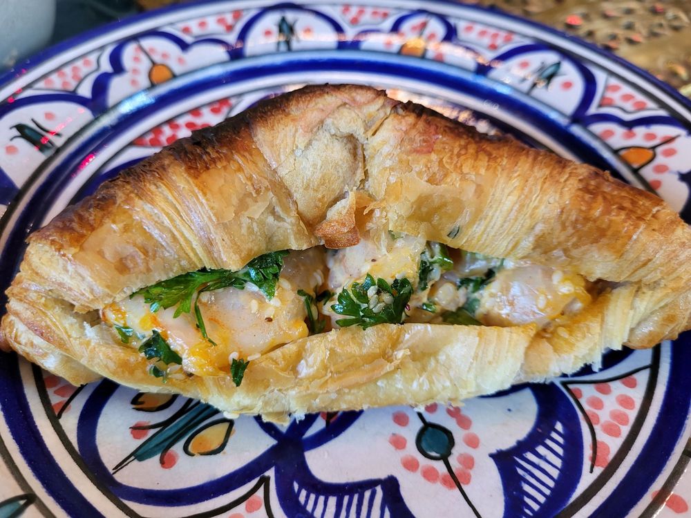 A savory shrimp croissant on a blue painted plate