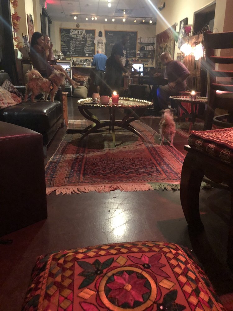An embroidered ottoman and lamp-lit tables in the evening