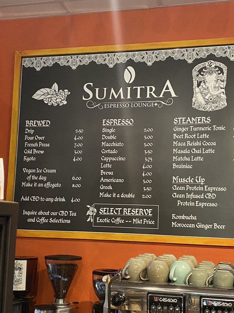 SumitrA's chalkboard menu over the espresso machine and a shelf of ceramic cups