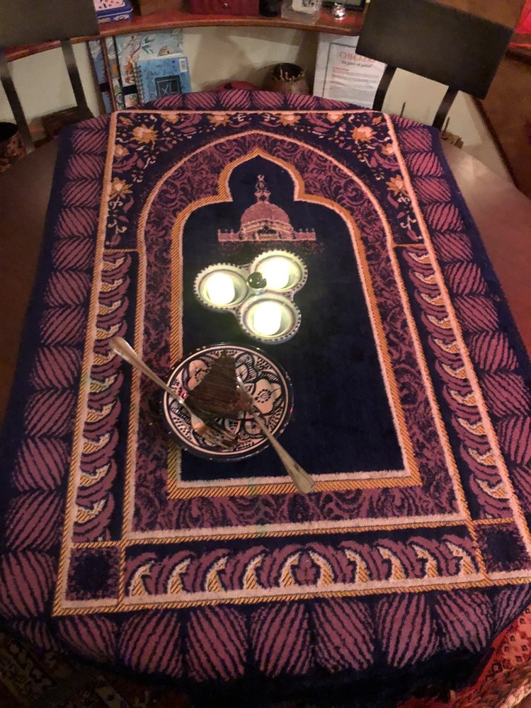 Overhead: candles and a dessert on a prayer-rug-patterned table