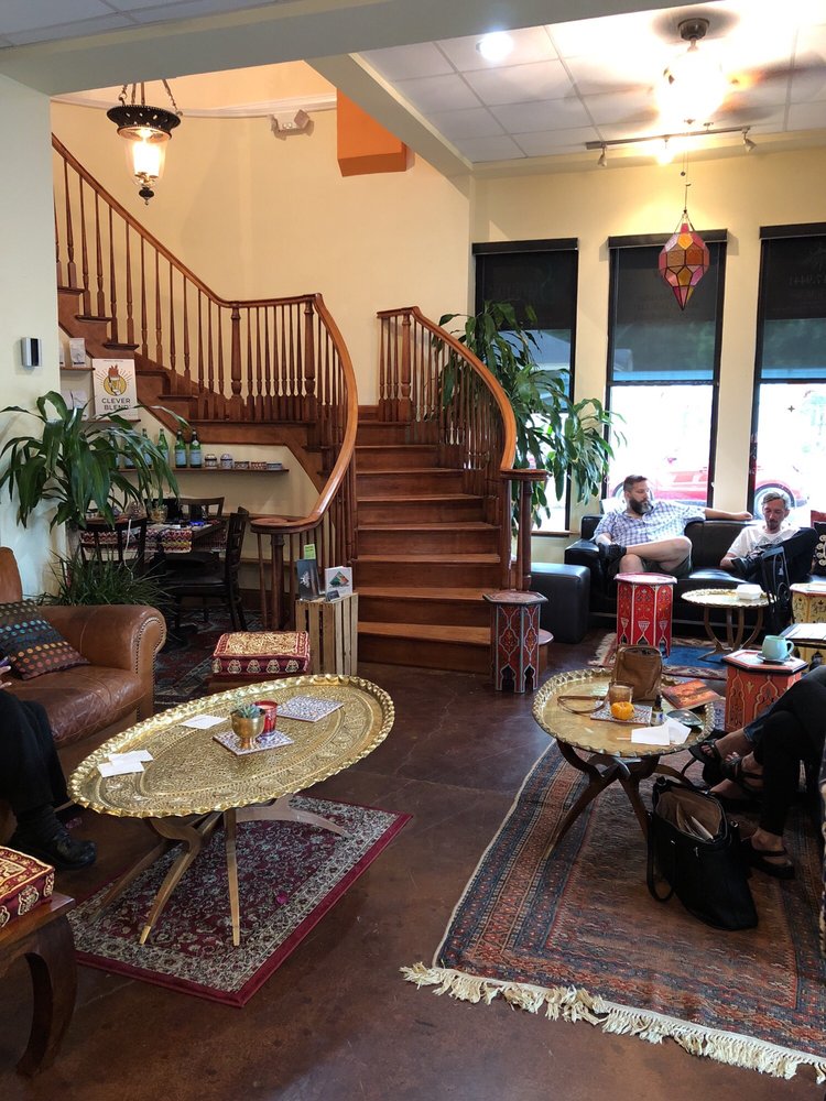 The staircase lounge in daylight, brass tray tables on layered rugs