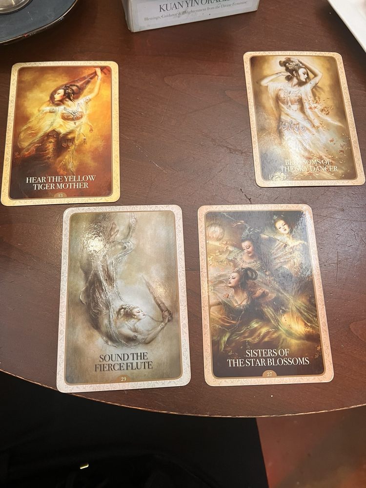 Four oracle cards laid out on a dark wooden table